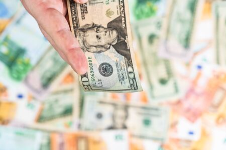 Hand giving money like bribe or tips isolated on banknotes background. EURO and USD currency banknotes close up. Reward for hard work, inflation, finance and business conceptの写真素材