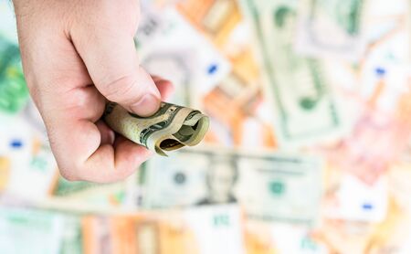 Hand giving money like bribe or tips isolated on banknotes background. EURO and USD currency banknotes close up. Reward for hard work, inflation, finance and business conceptの写真素材