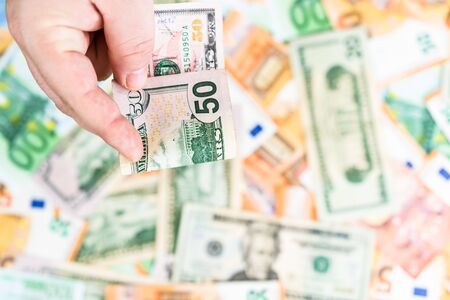 Hand giving money like bribe or tips isolated on banknotes background. EURO and USD currency banknotes close up. Reward for hard work, inflation, finance and business conceptの写真素材