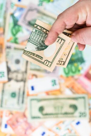 Hand giving money like bribe or tips isolated on banknotes background. EURO and USD currency banknotes close up. Reward for hard work, inflation, finance and business conceptの写真素材