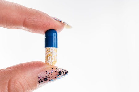 Hand holding antibiotics capsules or painkillers isolated on white. Medicine concept, pills close up, copy spaceの写真素材