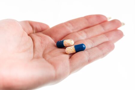 Hand holding antibiotics capsules or painkillers isolated on white. Medicine concept, pills close up, copy spaceの写真素材