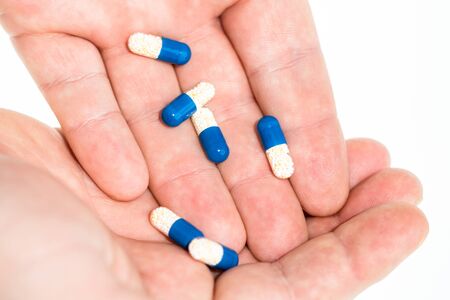 Hand holding antibiotics capsules or painkillers isolated on white. Medicine concept, pills close up, copy spaceの写真素材