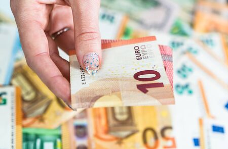 Hand giving money like bribe or tips isolated on banknotes background. EURO and USD currency banknotes close up. Reward for hard work, inflation, finance and business conceptの写真素材