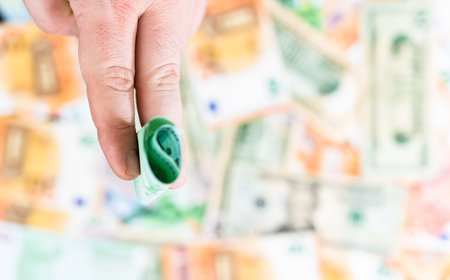 Hand giving money like bribe or tips isolated on banknotes background. EURO and USD currency...