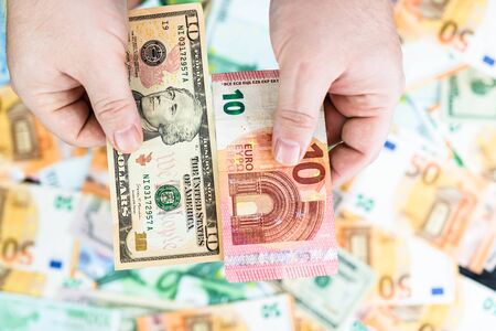 Hand holding money isolated on banknotes background. EURO and USD currency banknotes compared close up. Inflation, finance and business conceptの写真素材