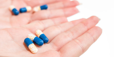 Hand holding antibiotics capsules or painkillers isolated on white. Medicine concept, pills close...