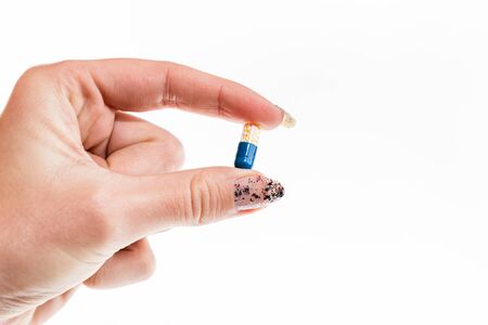 Hand holding antibiotics capsules or painkillers isolated on white. Medicine concept, pills close up, copy spaceの写真素材