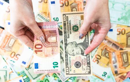 Hand holding money isolated on banknotes background. EURO and USD currency banknotes compared close up. Inflation, finance and business conceptの写真素材