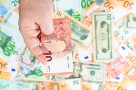 Hand giving money like bribe or tips isolated on banknotes background. EURO and USD currency banknotes close up. Reward for hard work, inflation, finance and business conceptの写真素材