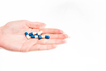 Hand holding antibiotics capsules or painkillers isolated on white. Medicine concept, pills close up, copy spaceの写真素材