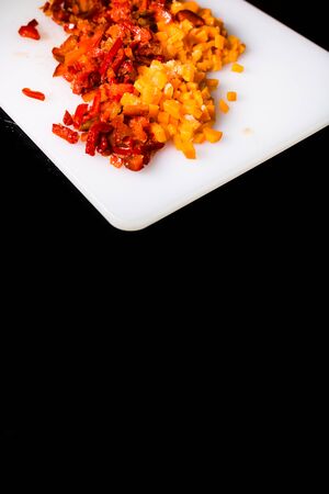Fresh and frozen chopped vegetables,  Chopped carrots  and red bell pepper on white cutting board.の写真素材