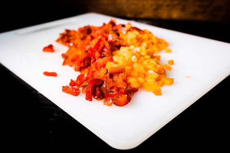 Fresh and frozen chopped vegetables,  Chopped carrots  and red bell pepper on white cutting board.の写真素材