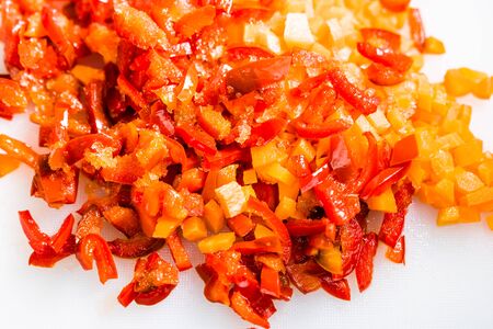 Fresh and frozen chopped vegetables,  Chopped carrots  and red bell pepper on white cutting board.の写真素材