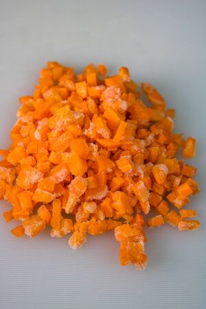 Fresh and frozen chopped vegetables,  Chopped carrots on white cutting board.の写真素材