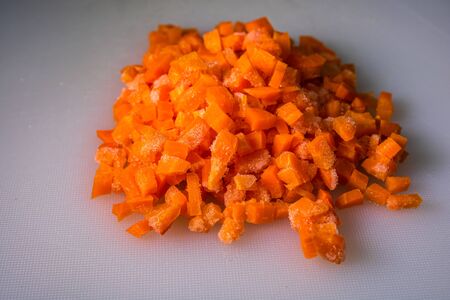 Fresh and frozen chopped vegetables,  Chopped carrots on white cutting board.の写真素材