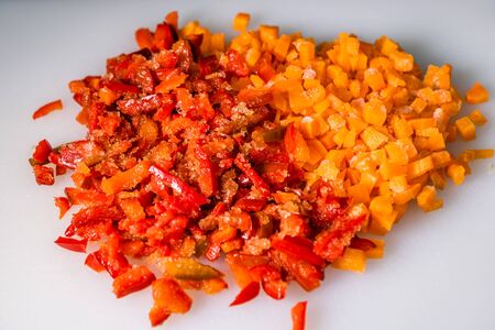 Fresh and frozen chopped vegetables,  Chopped carrots on white cutting board.の写真素材