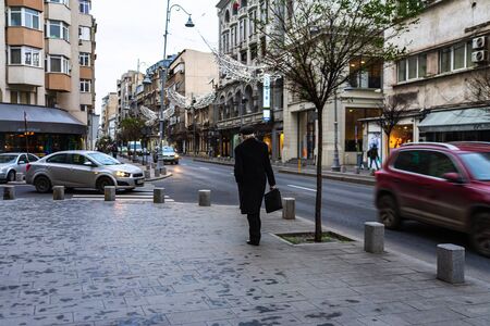 Man with black coat walking on the street on Victoriei Way in downtown Bucharest, Romania, 2020のeditorial素材