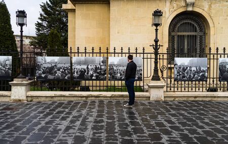 Man looking at the names of the heroes murdered at the 1989 Romanian Revolution on the fence of National Art Museum in Bucharest, Romania, 2020のeditorial素材