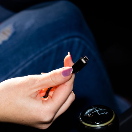 Close up shot of a woman's hand holding an usb cable in her car.の写真素材