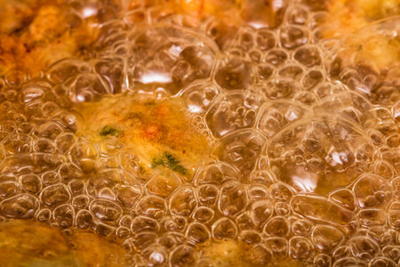 Close-up of hot boiling oil in skillet. Preparing homemade meatballs.