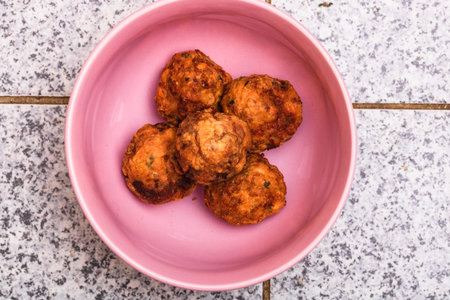 Pink bowl with fried meatballs with spices. Homemade food.