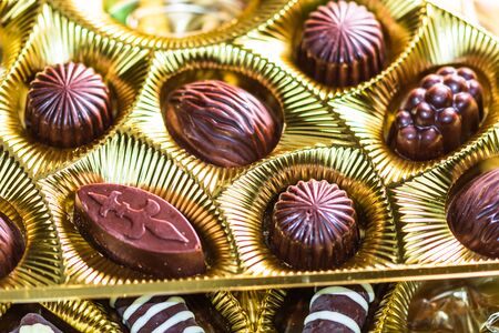 Variety of delicious chocolate pralines in a golden box. Close up of bonbons, selective focus.の写真素材