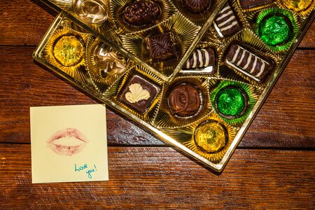 Love text on memo post reminder, near a golden box with chocolate pralines.の写真素材