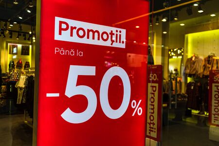 Discount, sale signs, red poster offer, mock up advertise display frame over clothes in shopping mall or department store for show promotion product at AFI Cotroceni Mall from Bucharest, Romania, 2020のeditorial素材