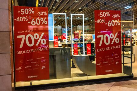 Discount, sale signs, red poster offer, mock up advertise display frame over clothes in shopping mall or department store for show promotion product at AFI Cotroceni Mall from Bucharest, Romania, 2020のeditorial素材