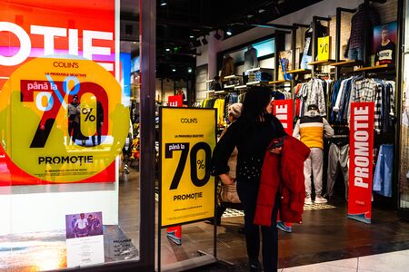Discount, sale signs, red poster offer, mock up advertise display frame over clothes in shopping mall or department store for show promotion product at AFI Cotroceni Mall from Bucharest, Romania, 2020のeditorial素材