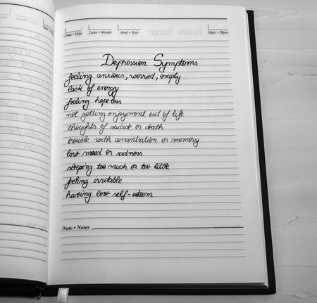 Depression symptoms, handwriting text on page of office agenda. Copy space.