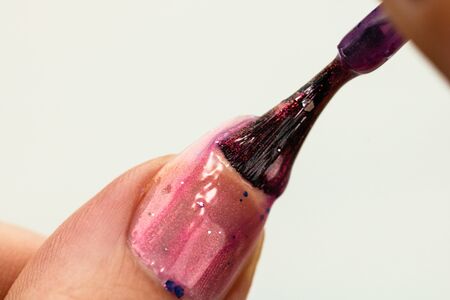 Female hands doing manicure, nail polish in gold glitter color on a white background. Skin and nail care salon conceptの写真素材