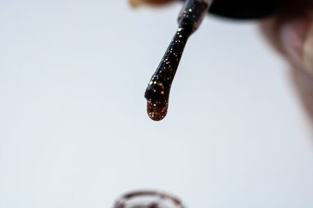 Female hands doing manicure, nail polish in gold glitter color on a white background. Skin and nail care salon conceptの写真素材