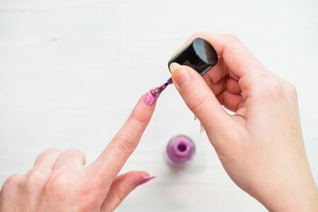 Female hands doing manicure, nail polish in gold glitter color on a white background. Skin and nail care salon conceptの写真素材