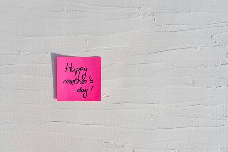 Handwriting text on memo post reminder. Happy mother`s day on paper, on white and textured wall.  Copy space.の写真素材