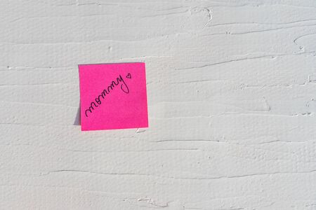 Handwriting text on memo post reminder. Mommy and heart on paper, on white and textured wall.  Copy space.の写真素材