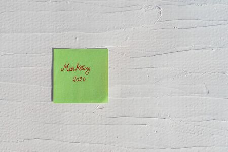 Handwriting text on memo post reminder. marketing 2020 on paper, on white and textured wall.  Copy space.の写真素材