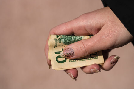 Hands giving money like a bribe or tips. Holding US dollars banknotes on a blurred background, US...