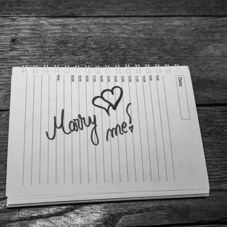 Marry me, writing love text on paper, lovely message. Text on spiral agenda. Romantic, love concept. Valentine`s day.の写真素材