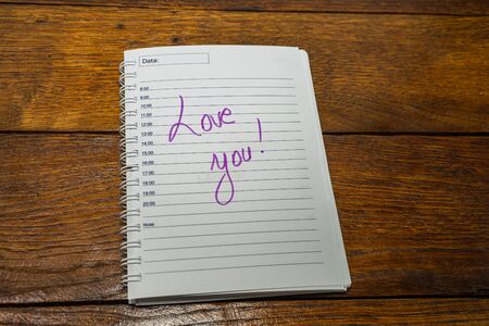 Love you, writing love text on paper, lovely message. Text on spiral agenda. Romantic, love concept. Valentine`s day.の写真素材