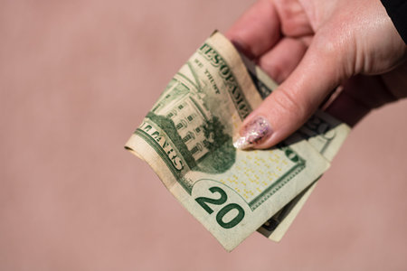 Hand holding or giving dollars money. Holding US dollars banknote on a blurred background, US...