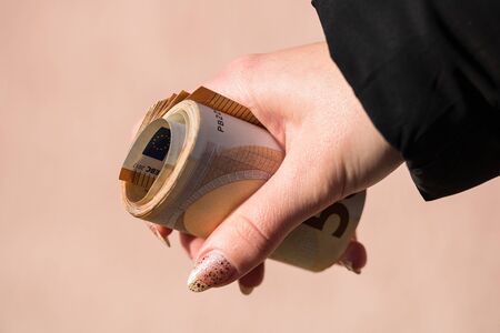 Hand holding rolled money, holding euro banknotes on a blurred background, EURO currency .の写真素材