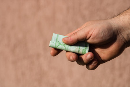 Man hands giving money like a bribe or tips. Holding EURO banknotes on a blurred background, EU...