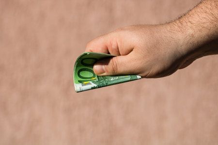Man hands giving money like a bribe or tips. Holding EURO banknotes on a blurred background, EU currencyの写真素材