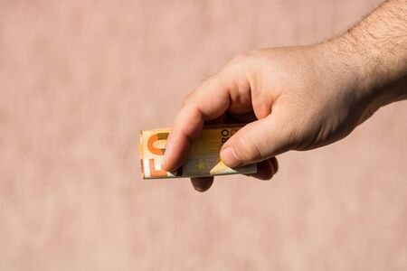 Man hands giving money like a bribe or tips. Holding EURO banknotes on a blurred background, EU currencyの写真素材