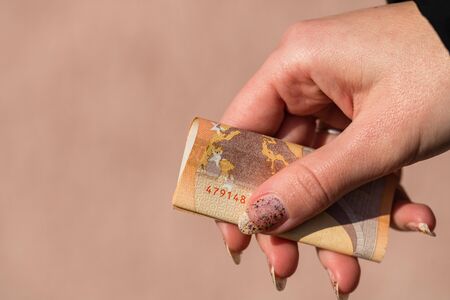 woman hands giving money like a bribe or tips. Holding EURO banknotes on a blurred background, EU currencyの写真素材