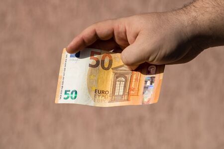 Man hands giving money like a bribe or tips. Holding EURO banknotes on a blurred background, EU currencyの写真素材