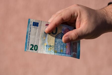 Man hands giving money like a bribe or tips. Holding EURO banknotes on a blurred background, EU currencyの写真素材