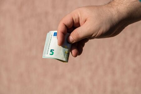 Man hands giving money like a bribe or tips. Holding EURO banknotes on a blurred background, EU currencyの写真素材